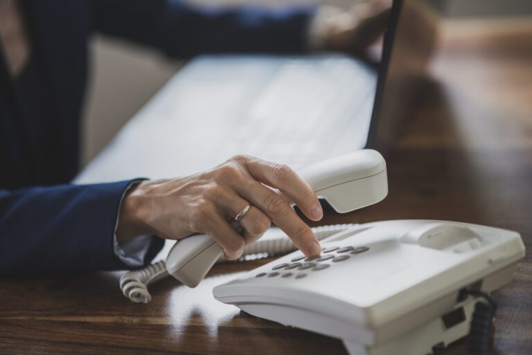 Worker at desk dialing phone to test church phone system reliability and connection quality.